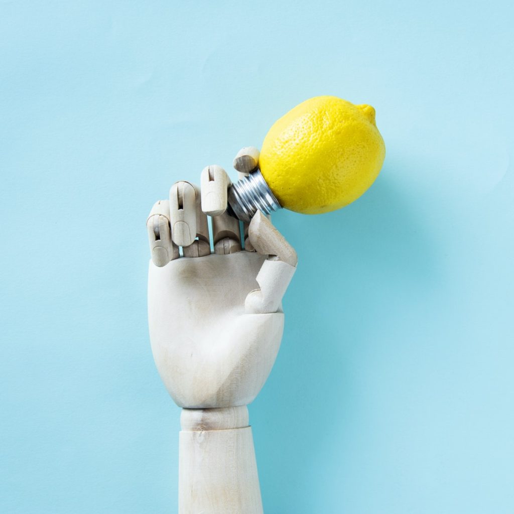 robot hand holding light bulb lemon 