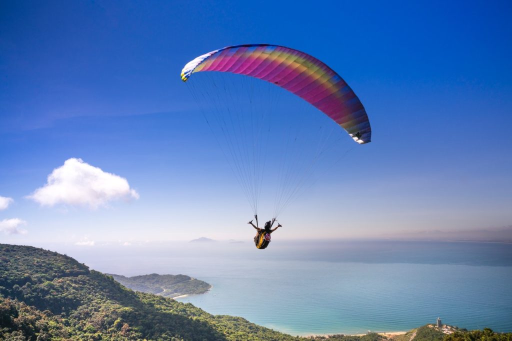 men parachuting in front of beautiful ocean view 